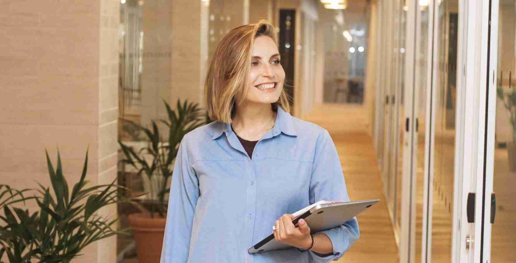 lachende-vrouw-laptop-in-hand-blauwe-blouse-werk