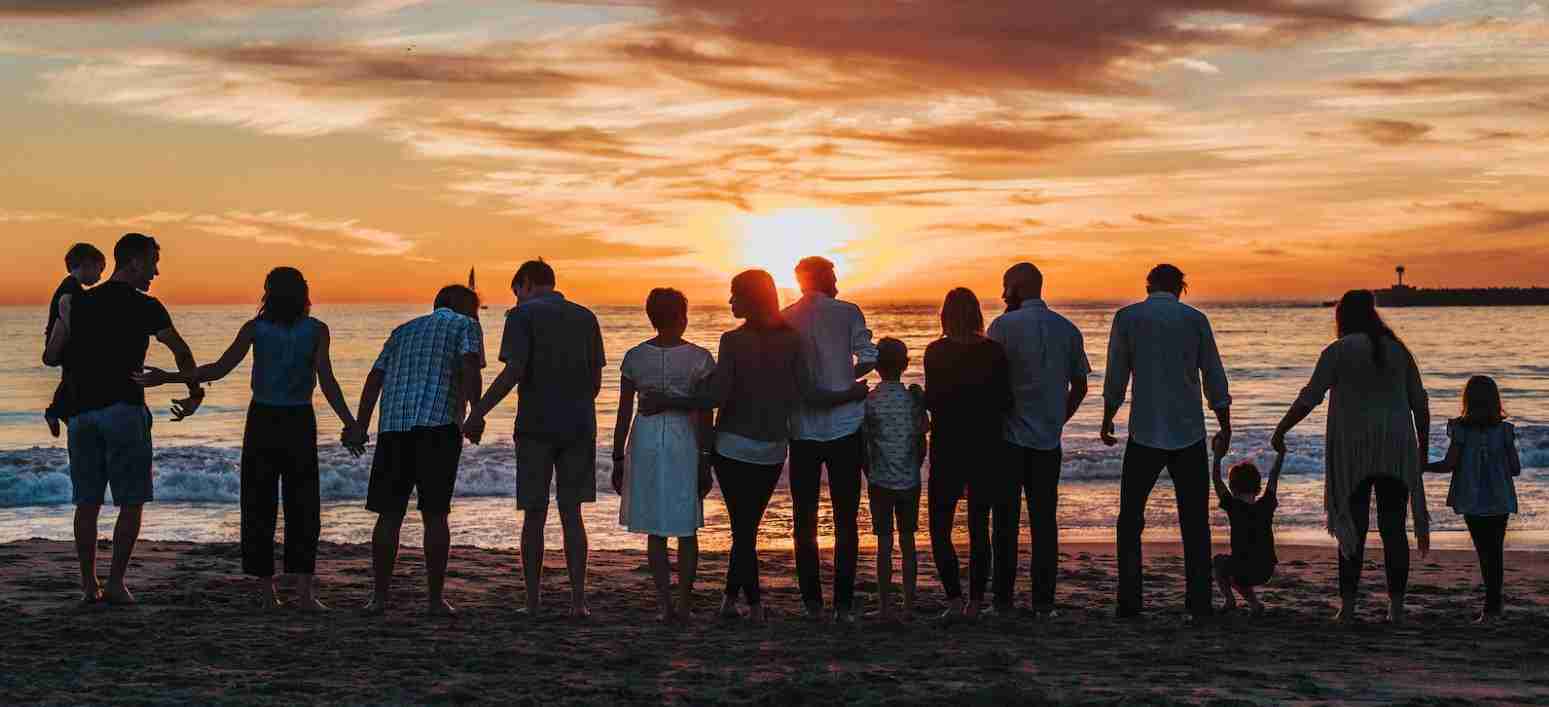 grote-familie-op-strand-zonsondergang