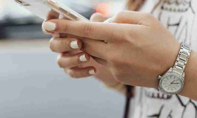 vrouwen-hand-telefoon-horloge-gelakte-nagels