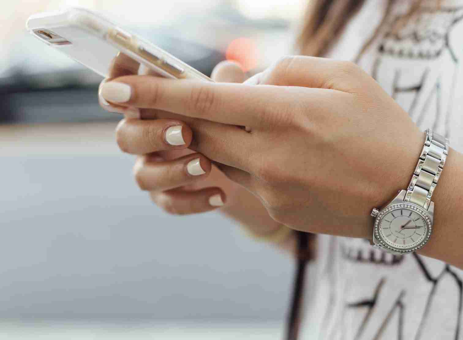 vrouwen-hand-telefoon-horloge-gelakte-nagels