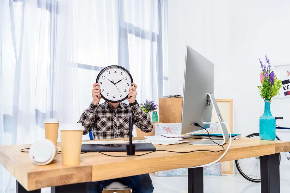 man houdt klok voor zijn hoofd