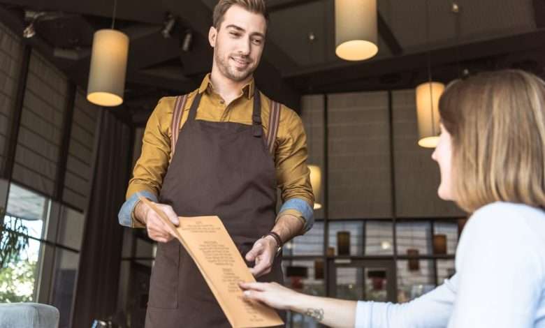 mannelijke serveerder geeft menu kaart aan vrouw