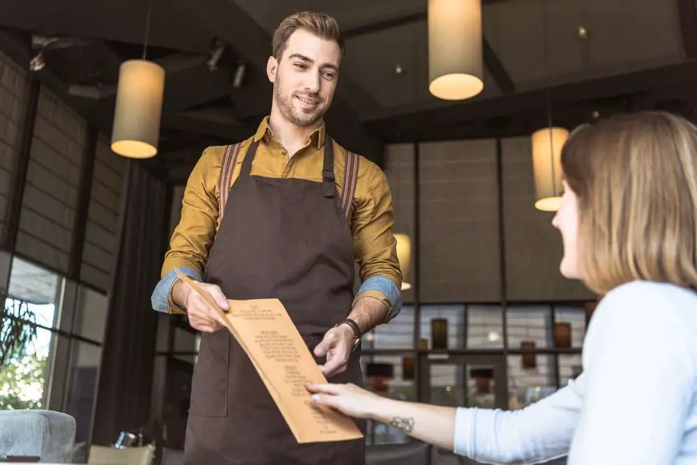 mannelijke serveerder geeft menu kaart aan vrouw