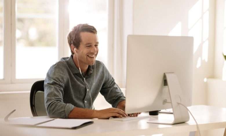 Man Met Oordopjes In Lachend Achter De Computer