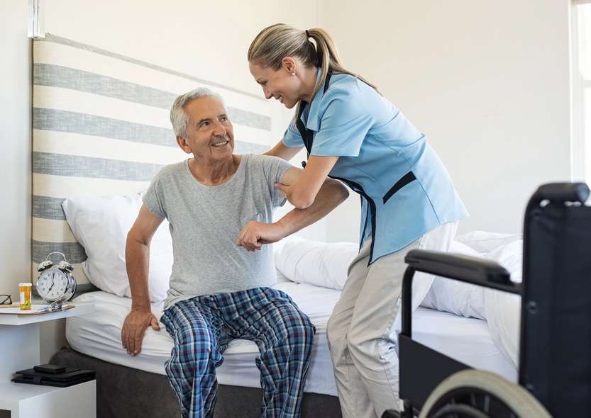 Vrouw Helpt Oudere Man Uit Bed Komen Thuiszorg
